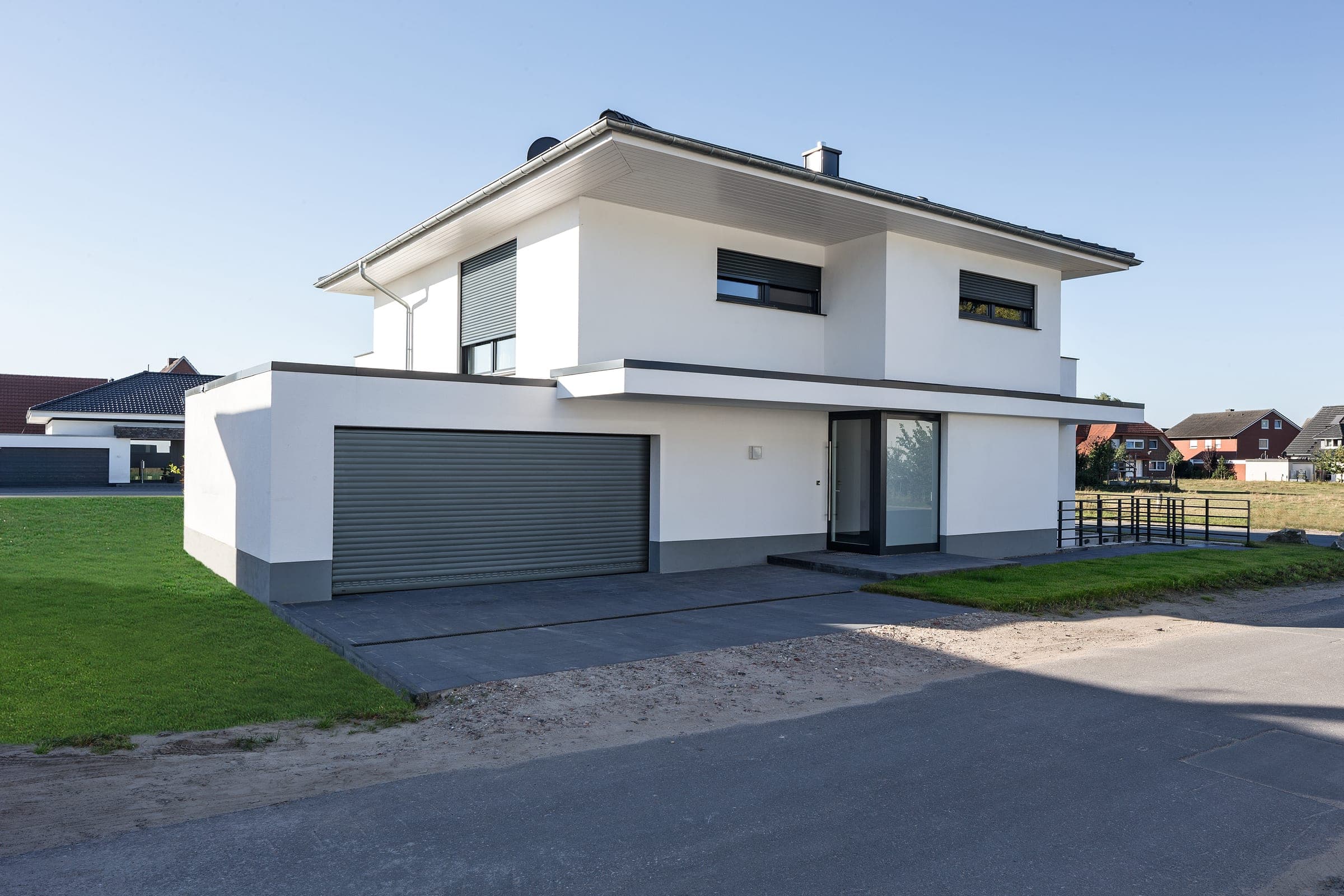 Maison neuve crépie moderne équipée de volets roulants Alulux aux fenêtres et au garage