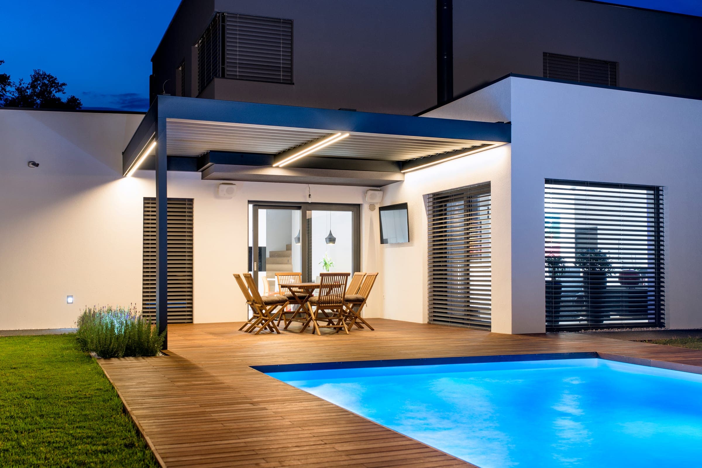 Maison moderne de nuit avec raffstores Alulux aux fenêtres et à la terrasse