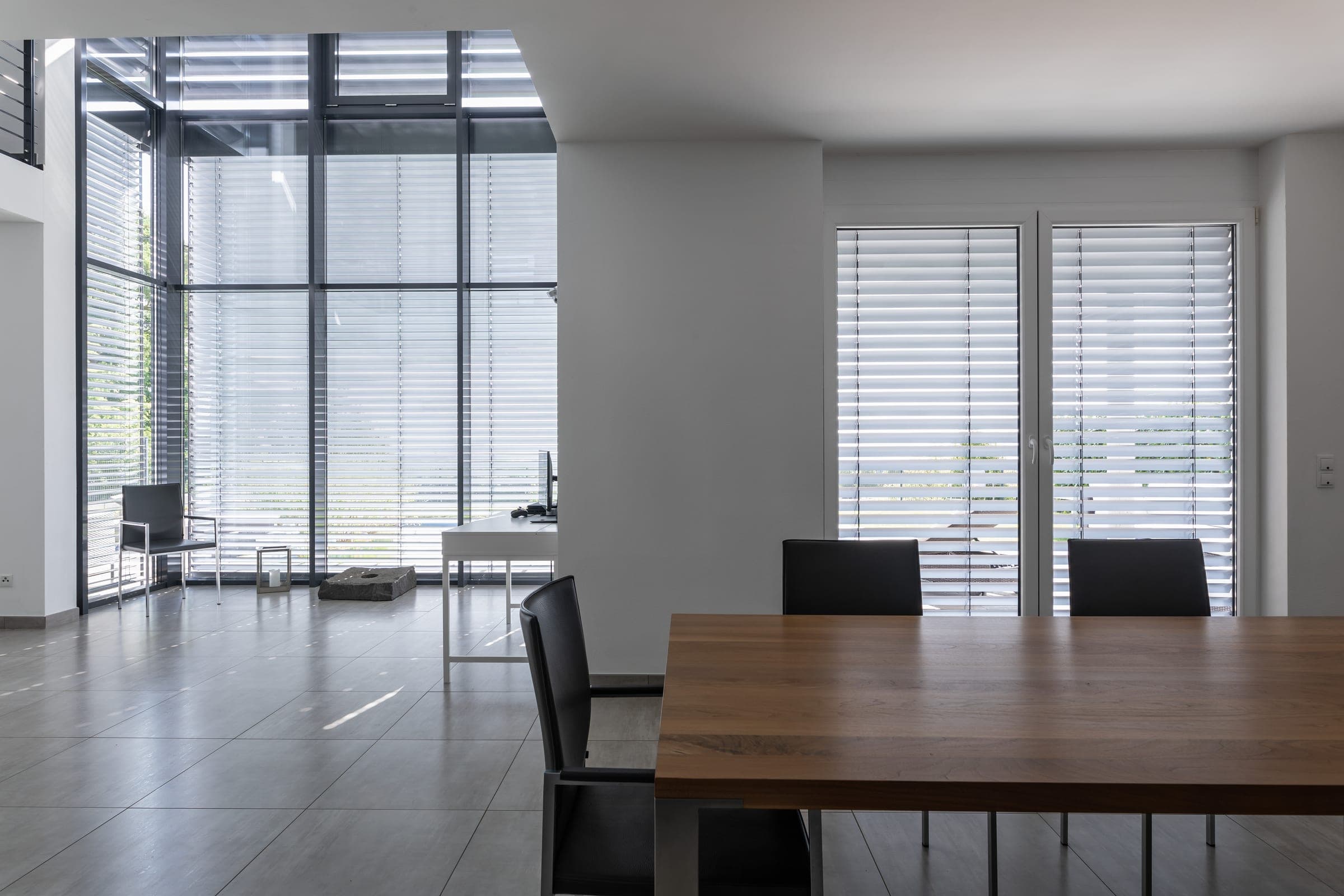 Fenêtres toute hauteur avec raffstores Alulux dans un salon moderne