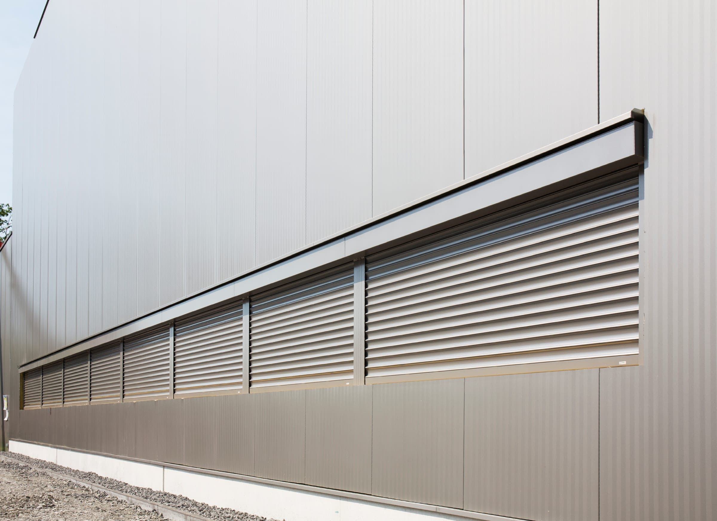 Breites Band aus Qompact Sicherheitsrollladen an einer industriellen Metallfassade