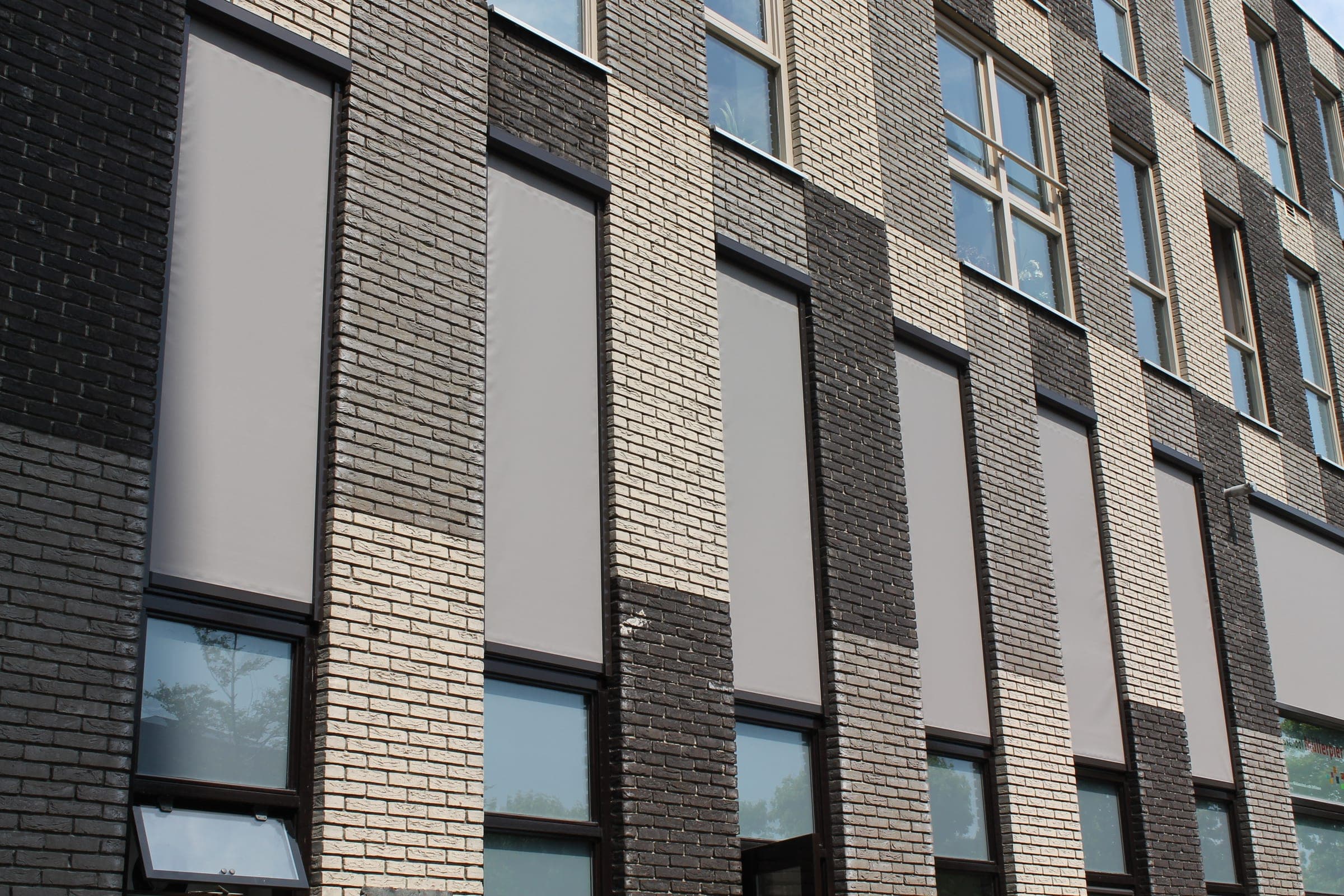 Klinkerfassade mit mehreren heruntergelassenen Alulux Unterputz-Textilscreens