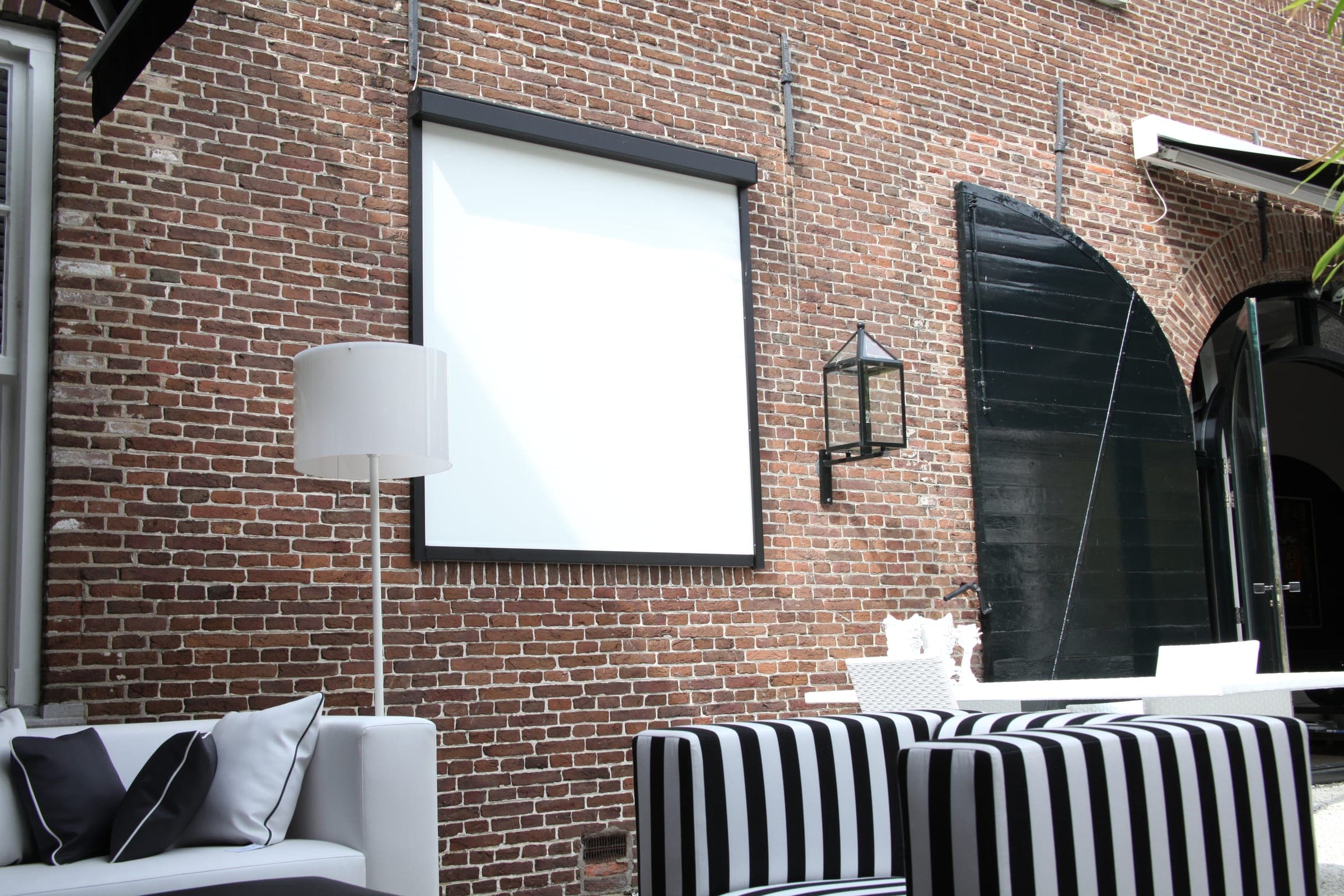 Xtrazip Textilscreen an einer Backsteinwand über einer Loungeterrasse