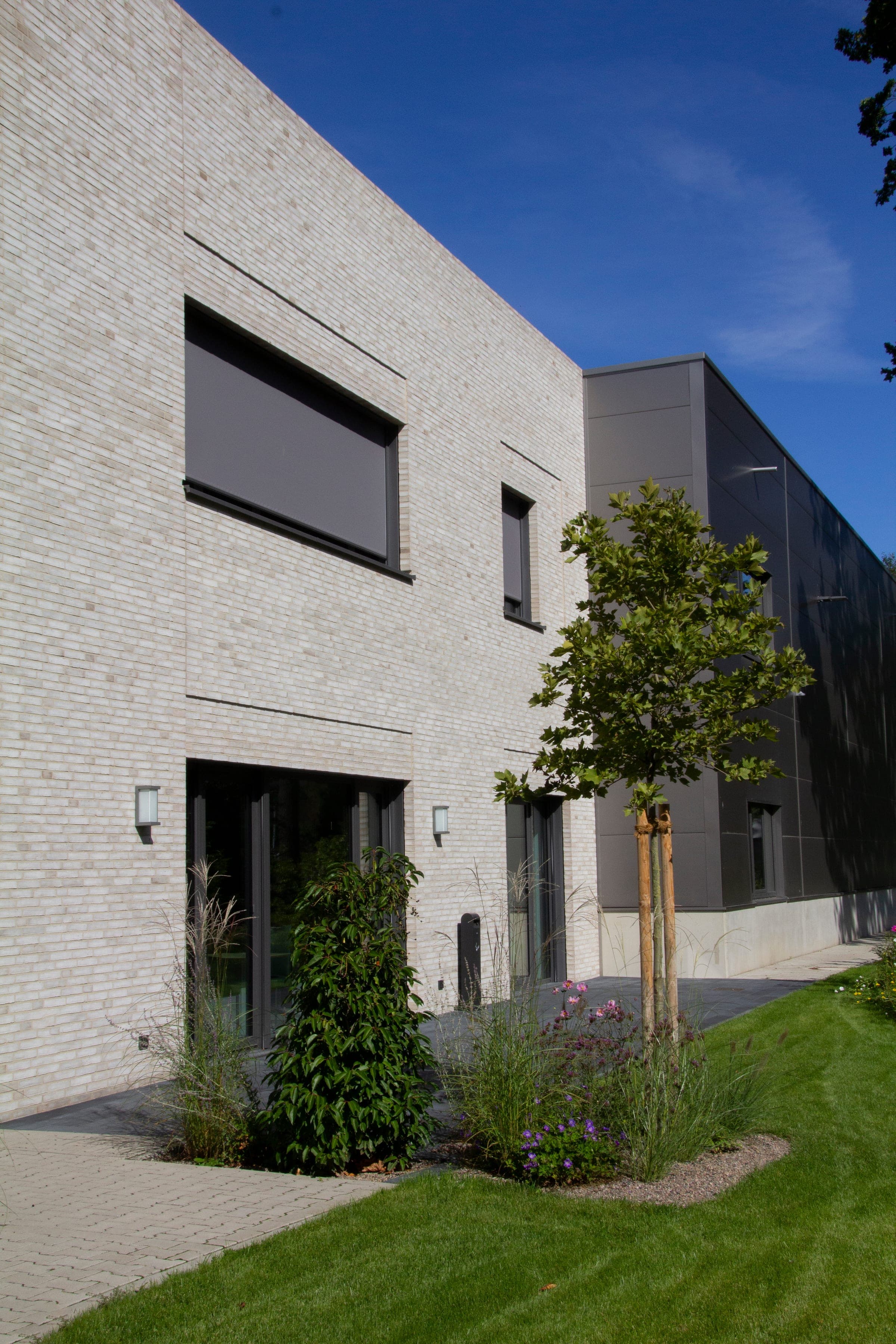 Moderne Klinkerarchitektur mit Xtrazip Textilscreens an großen Fensterflächen
