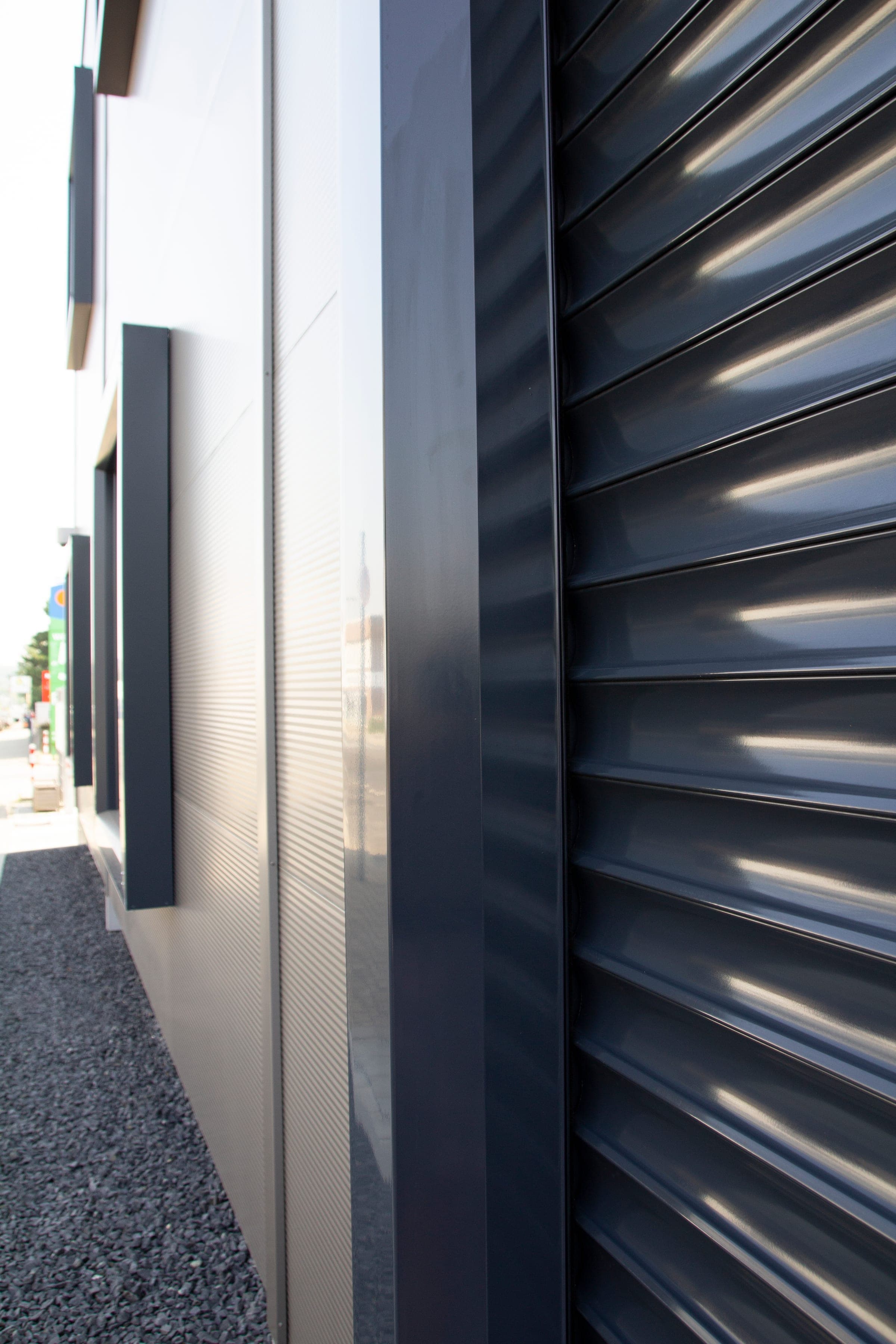 Alulux Qompact Sicherheitstor mit anthrazitfarbenen Aluminiumlamellen an einer Fassade