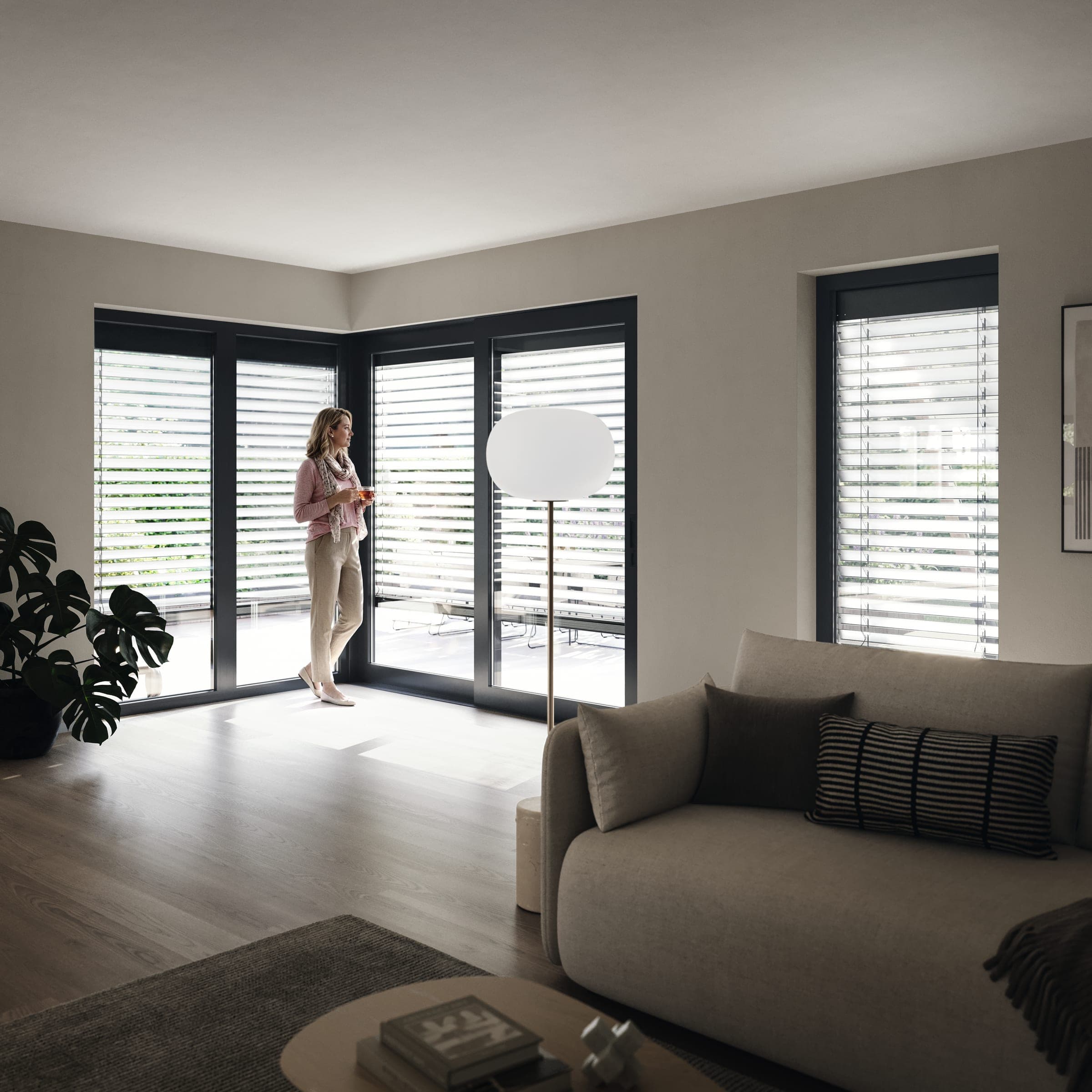 Heller Wohnraum mit bodentiefen Fenstern und gekippten Alulux Raffstore-Lamellen