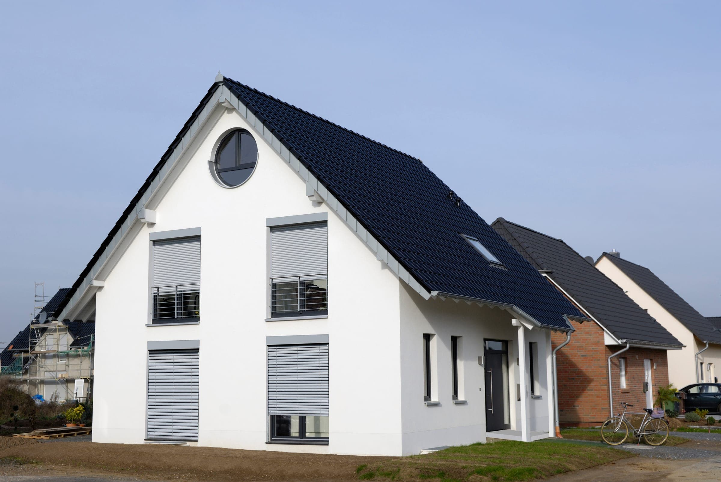 Weißes Einfamilienhaus mit heruntergefahrenen Alulux Raffstoren an den Fenstern