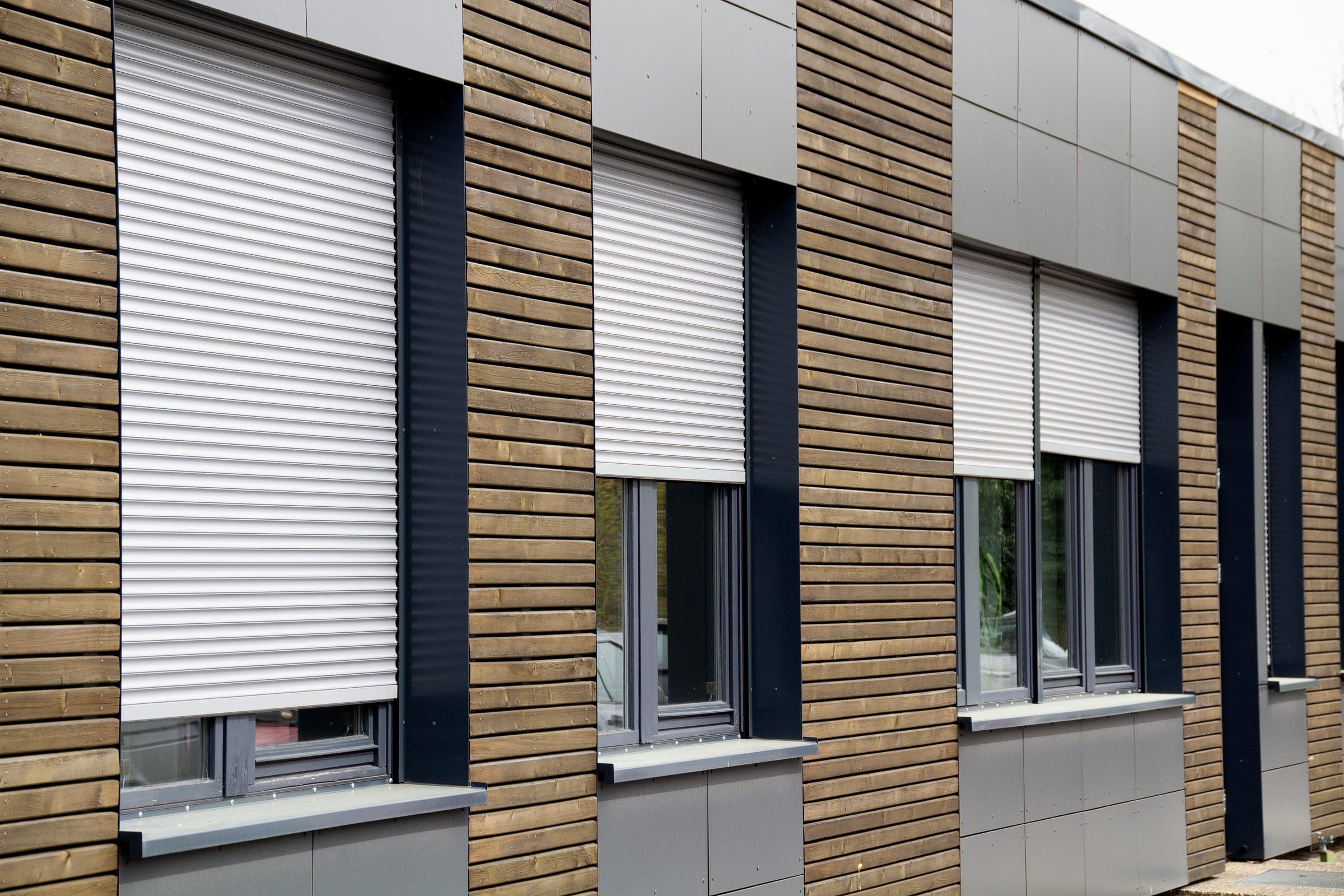 Modernes weißes Mehrfamilienhaus mit Alulux Vorbaurollladen an mehreren Fenstern der Fassade
