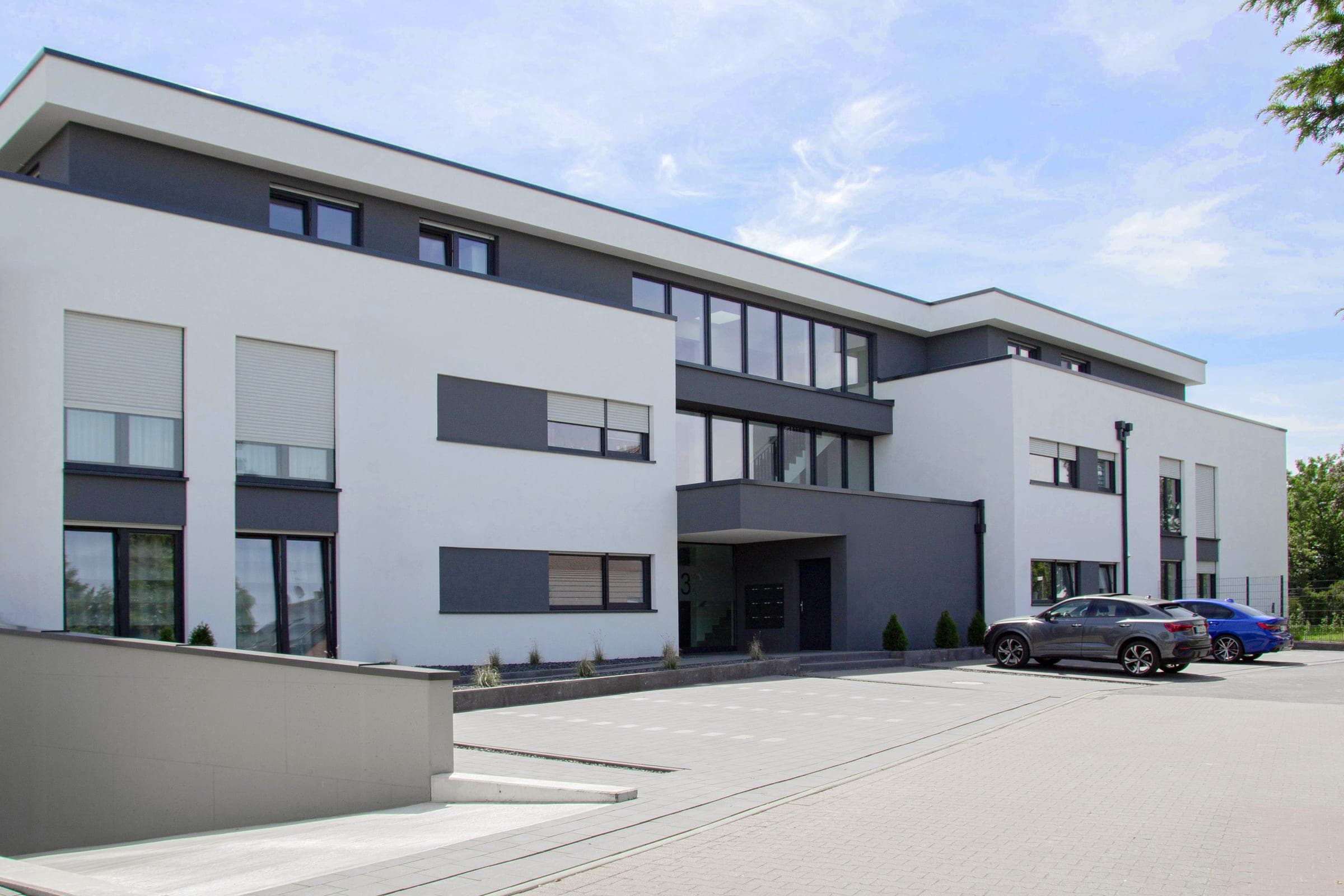 Moderne holzverkleidete Fassade mit heruntergelassenen weißen Alulux Rollladen an den Fenstern