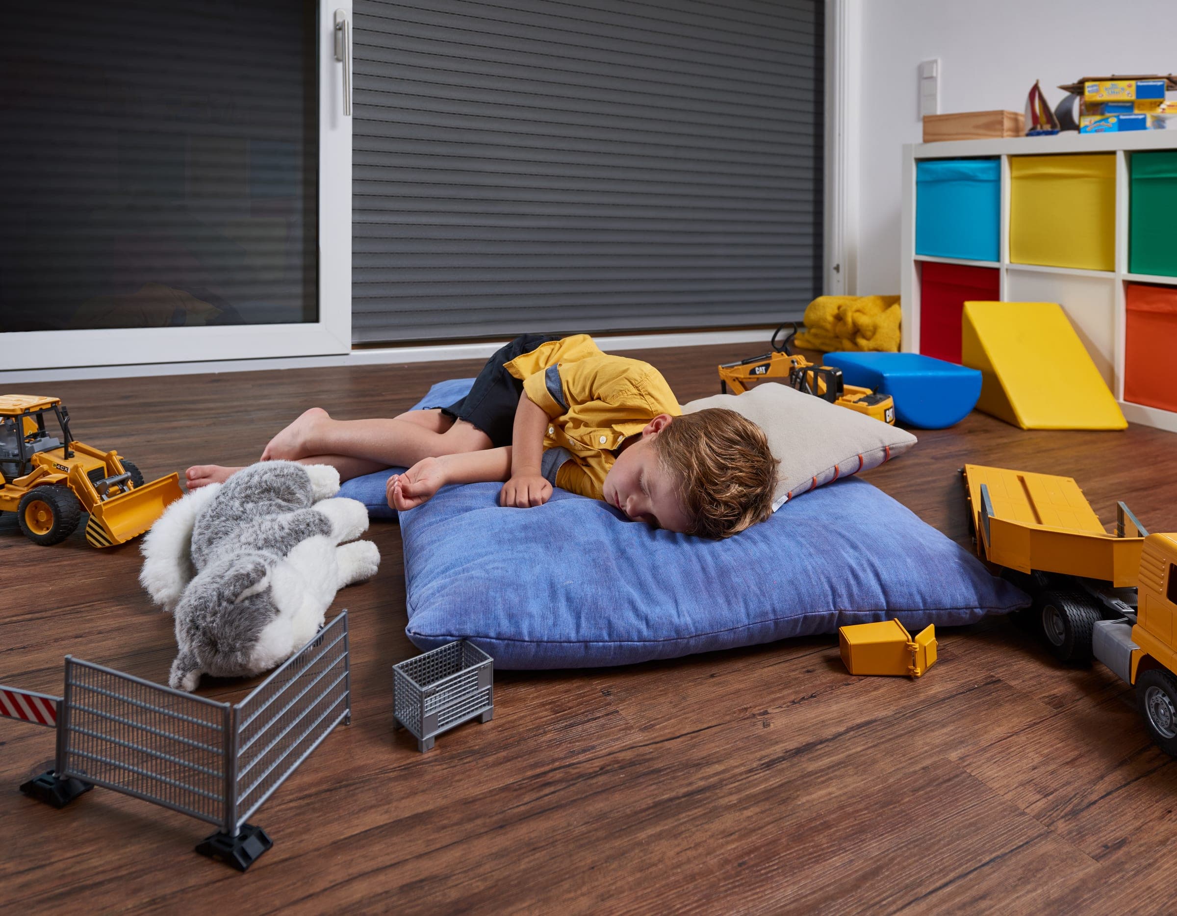 Helles Kinderzimmer mit halb geschlossenem Alulux Rollladen am bodentiefen Fenster