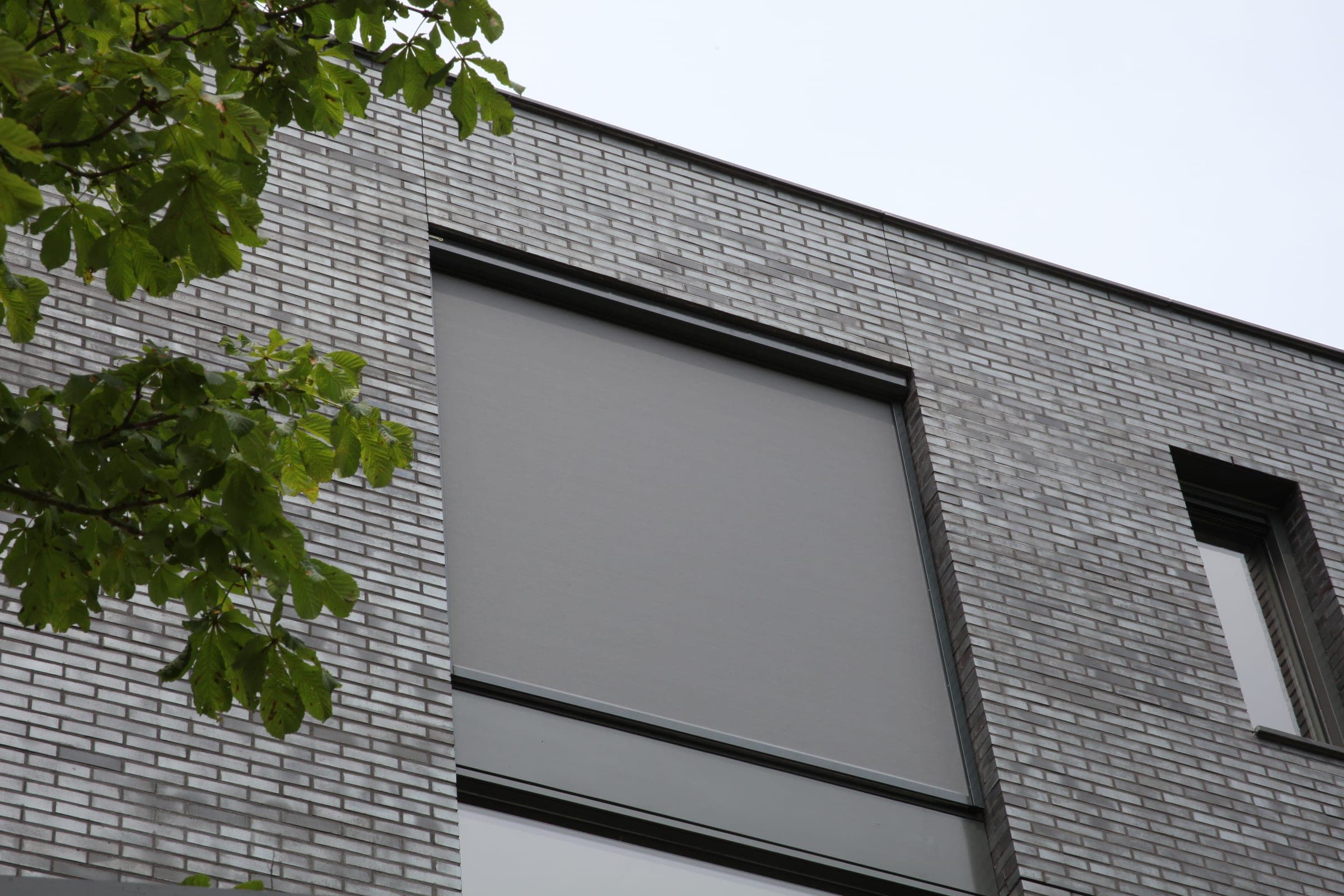 Moderne graue Klinkerfassade mit bündig integriertem Alulux Textilscreen