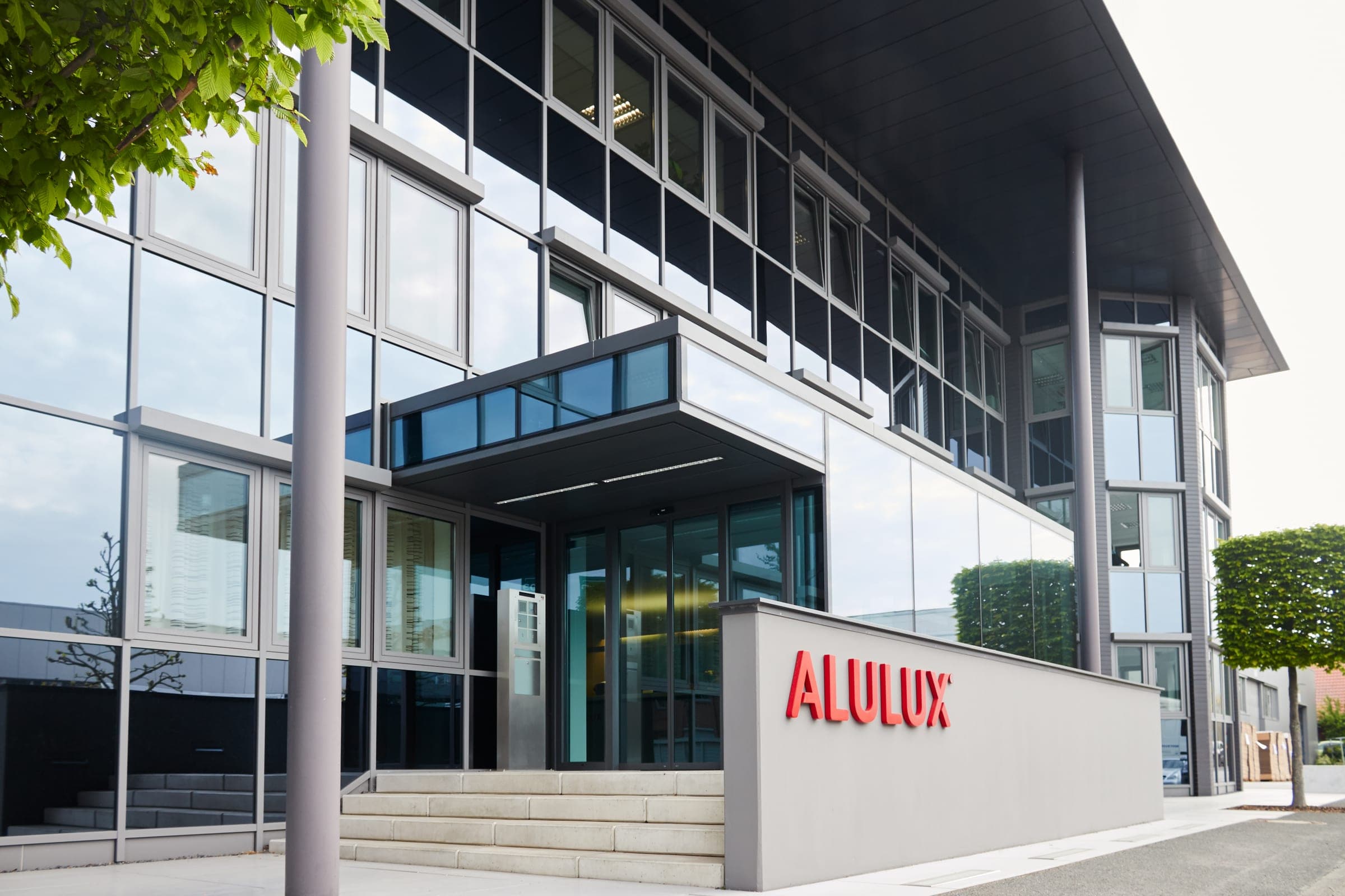 Bâtiment de l’entreprise ALULUX sur le site de Verl, avec le logo ALULUX rouge à l’entrée